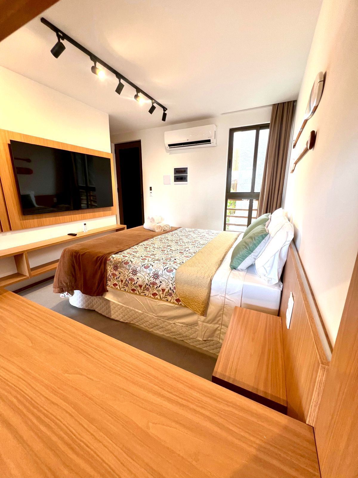 A modern hotel room with a large bed, a flat-screen TV, a desk, and a window.