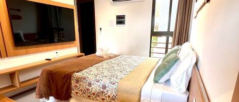 A modern hotel room with a large bed, a flat-screen TV, a desk, and a window.