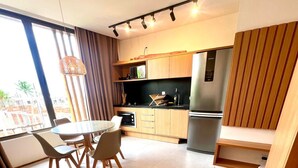 A modern kitchen with a dining area, large windows, and a view of the outside. - Seaside Studio II at “ecologic route of Milagres (Porto de Pedras)