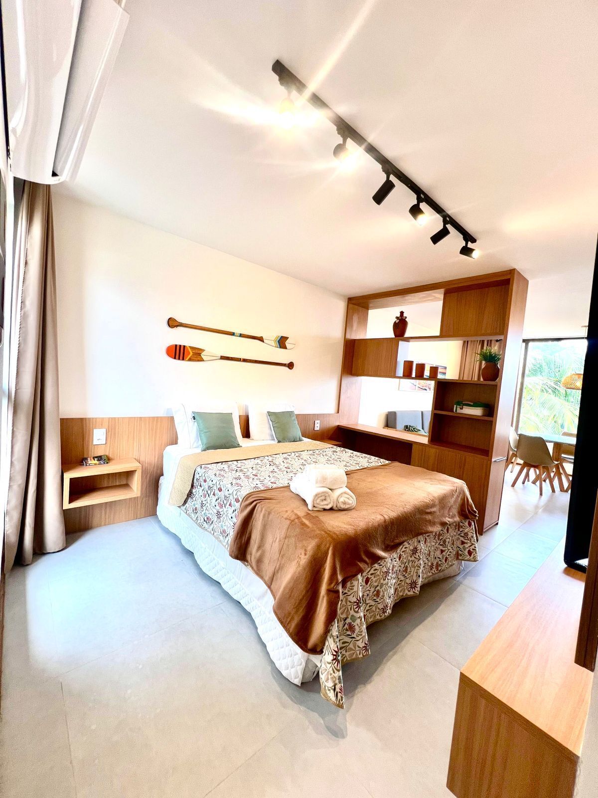 Un dormitorio moderno con cama, mesitas de noche, escritorio empotrado y vistas al exterior.