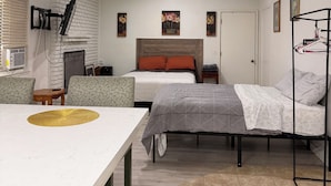 Un dormitorio con dos camas, un escritorio, una silla, un televisor y una mesita.