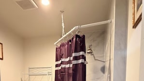 Un baño con ducha, inodoro y un tendedero de metal.