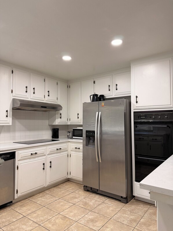 A kitchen with white cabinets, stainless steel appliances, and a tiled floor.