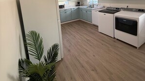 A kitchen with light blue cabinets, a white refrigerator, a stove, and a washing machine. - Newly Renovated 3 Bedroom House in Lakewood (Durham)