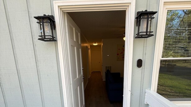 A house entrance with a number '2605' above the door, a wooden deck, and a blue couch inside. - Newly Renovated 3 Bedroom House in Lakewood (Durham)