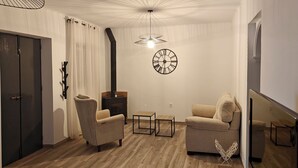 A living room with two armchairs, a small table, a fireplace, a clock, and a staircase. - Villa Bellavista (Olvera)