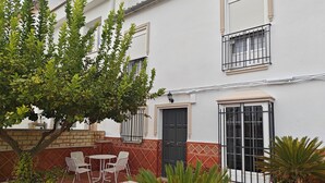 A courtyard with a table and chairs, a potted plant, and a building with a door and windows. - Villa Bellavista (Olvera)