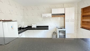 Een kleine keuken met witte kastjes, een zwart aanrecht, een gasfornuis en een inbouwoven.