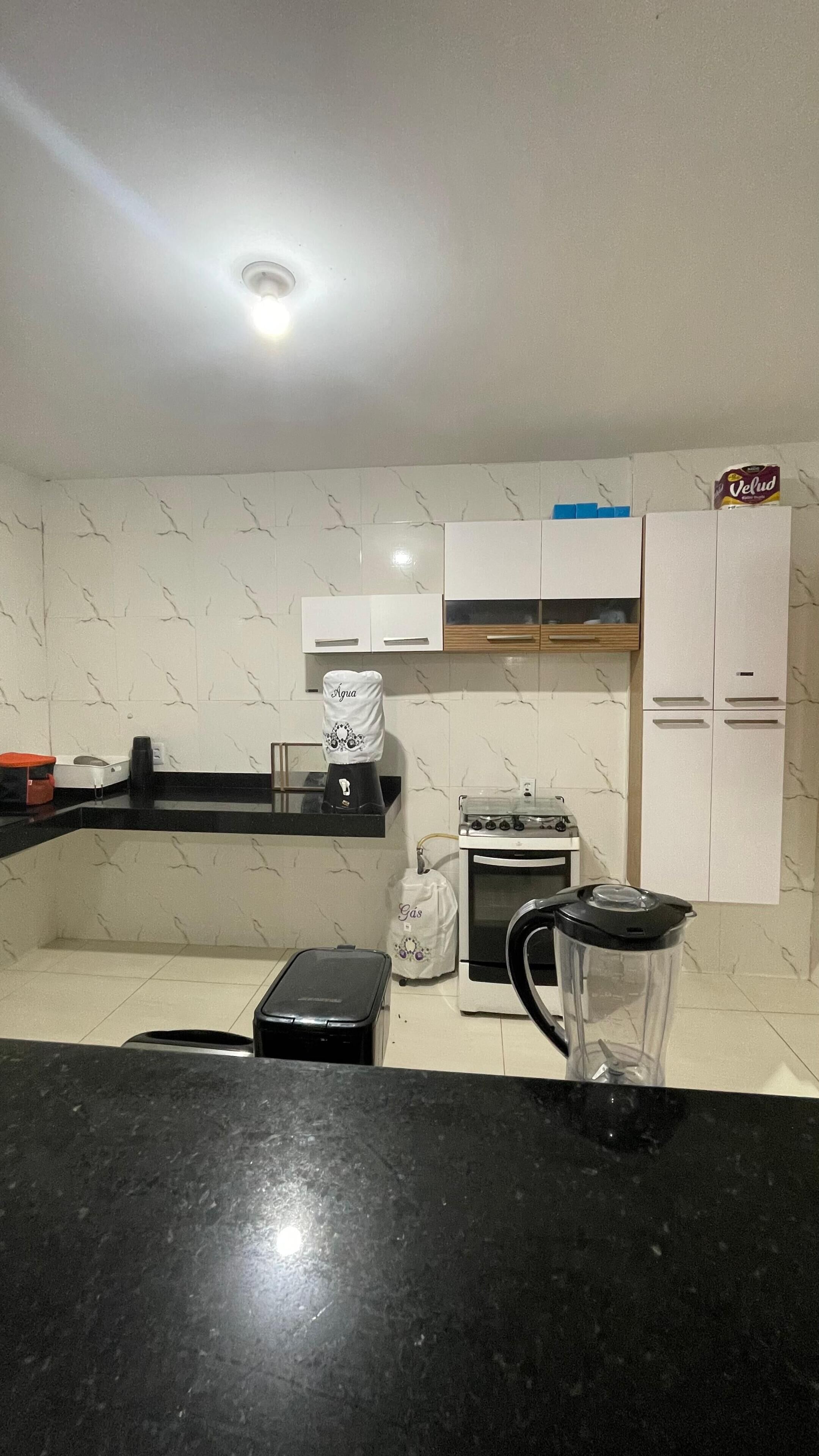 Uma cozinha com armários brancos, fogão, chaleira e cafeteira.