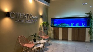 A reception area with a sign, a large aquarium, and seating. - Hotel Ciento Once Boutique (Medellín)