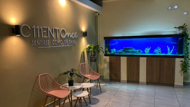 A reception area with a sign, a large aquarium, and seating. - Hotel Ciento Once Boutique (Medellín)