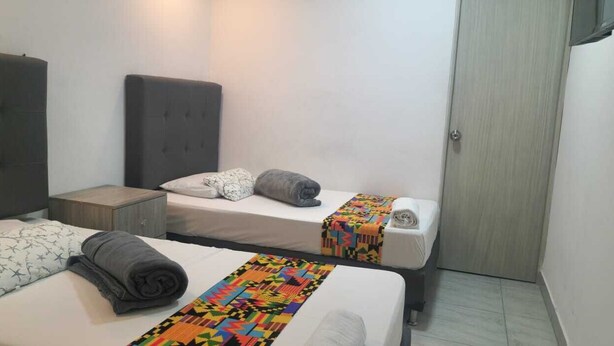 A hotel room with two beds, a wardrobe, and a small bedside table. - Hotel Ciento Once Boutique (Medellín)