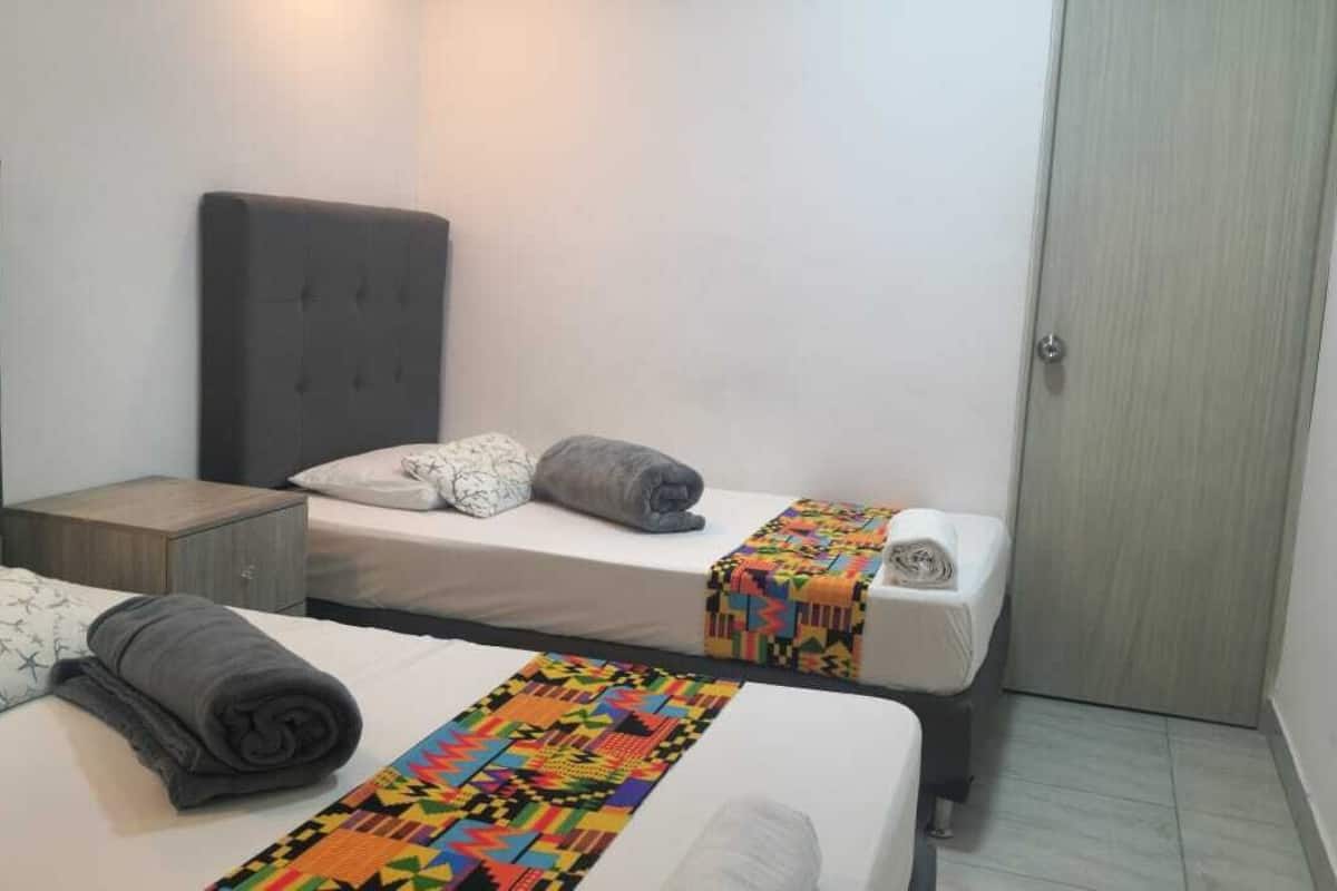 Une chambre d’hôtel avec deux lits, une armoire et une petite table de chevet.