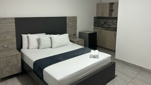 A modern bedroom with a bed, bedside tables, a built-in wardrobe, and a kitchenette. - Hotel Ciento Once Boutique (Medellín)