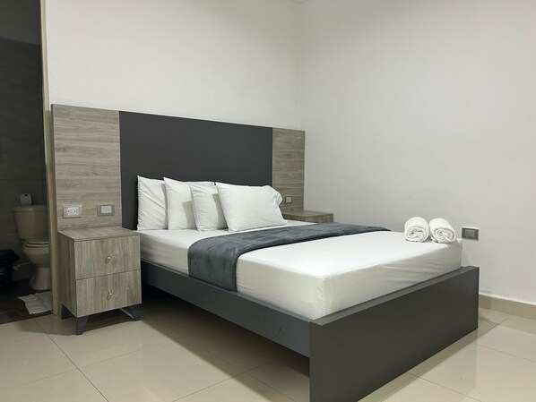 Une chambre à coucher moderne avec un lit, des tables de chevet et une commode.