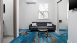 A modern living room with a sofa, a round coffee table, and a large window. - Plush Hotel (toronto)