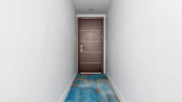 Um corredor estreito com piso azul e porta marrom no final.