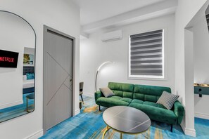 Una sala de estar moderna con un sofá verde, una mesa de centro redonda y un televisor montado en la pared.