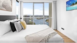A modern bedroom with a large bed, a city view, and a painting on the wall. - chevron /3beds / Pool /Parking n Ocean glimpses (Surfers Paradise)