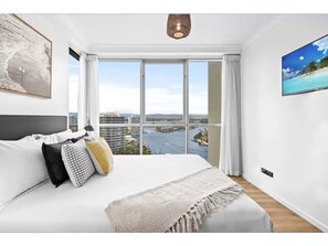 A modern bedroom with a large bed, a city view, and a painting on the wall. - chevron /3beds / Pool /Parking n Ocean glimpses (Surfers Paradise)