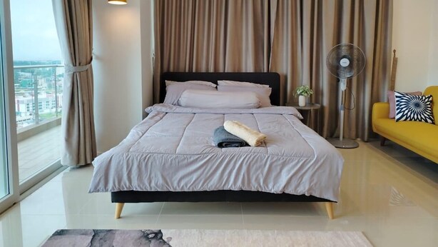 Un dormitorio moderno con cama, cortinas, un ventilador de pie y vistas a través de un ventanal amplio.