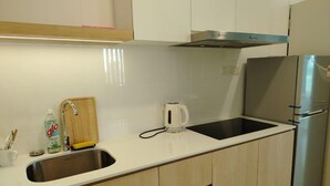 Una cocina con un lavamanos de acero inoxidable, un hervidor, un refrigerador y armarios de madera.