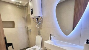A modern bathroom with a toilet, sink, shower, and a unique wall-mounted mirror. - Cocon Plaza (Marrakech)