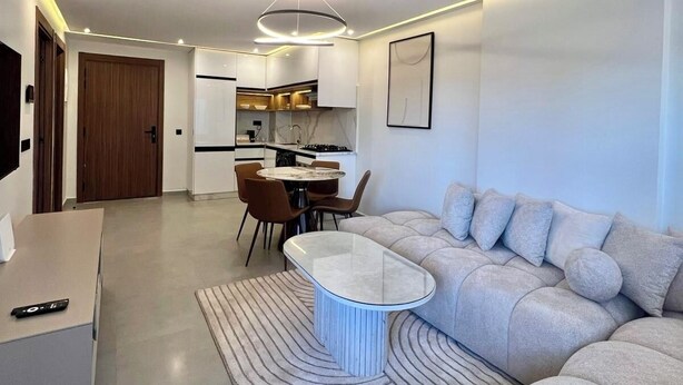 A modern living room with a sofa, a coffee table, and a dining area with chairs. - Cocon Plaza (Marrakech)