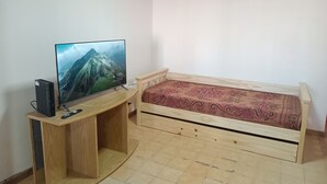 Una habitación con una cama de madera, un televisor sobre un mueble de madera y un escritorio pequeño.