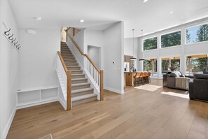 A spacious living area with a staircase, a dining area, and large windows. - Ridge House- new home, sleeps 16, quiet neighborhood-, hot tub, trailer parking, pet friendly (McCall)