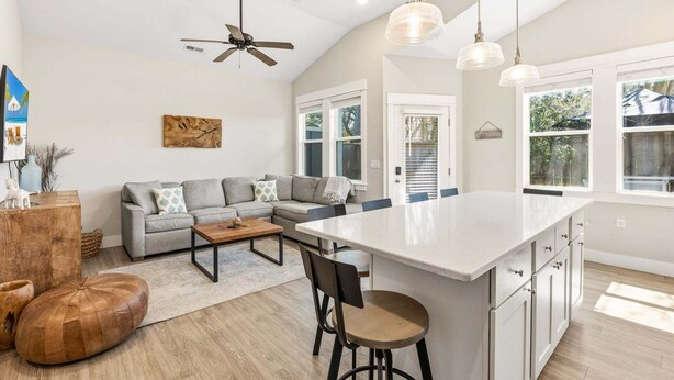 A modern kitchen with a large island, a ceiling fan, pendant lights, and a view of the outdoors. - BQ1B - Cozy Corolla Retreat Near Beach & Community Pool (Corolla)