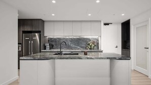 A modern kitchen with a curved island, built-in appliances, and a marble backsplash. - Ocean Glimpse - A 3-Bedroom Designer Sub-Penthouse @ 333STK (Port Phillip)