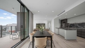 A modern apartment with a dining area, kitchen, and large balcony with a view. - Ocean Glimpse - A 3-Bedroom Designer Sub-Penthouse @ 333STK (Port Phillip)