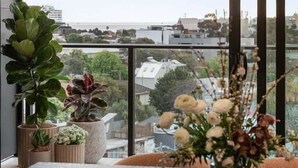 A modern interior with a large window, a dining table, and various potted plants. - Ocean Glimpse - A 3-Bedroom Designer Sub-Penthouse @ 333STK (Port Phillip)