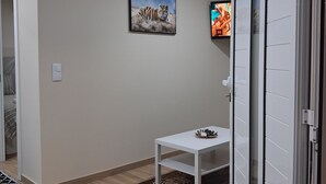 A room with a white table, a framed picture on the wall, and an air conditioning unit. - Arco-Íris, Ponta do Sol (Ponta do Sol)