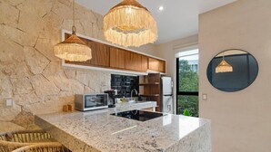 Una cocina moderna con una isla de mármol, armarios de madera y una pared de piedra.