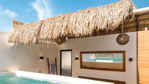 Una piscina con techo de paja, una puerta y un ventanal enmarcado.