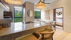 Una cocina moderna con una isla grande, dos lámparas colgantes y vistas al exterior.