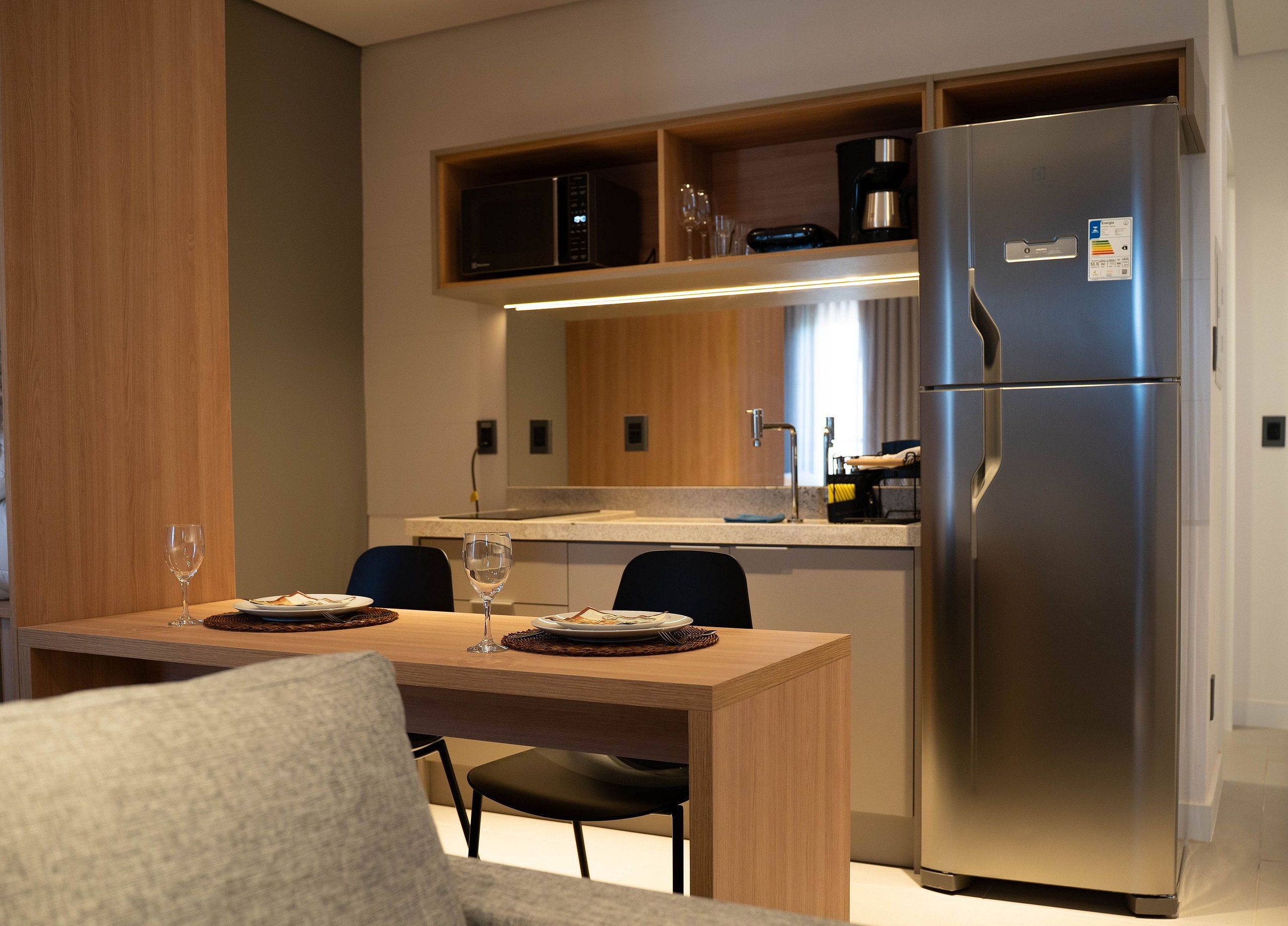 Una cocina moderna con microondas integrado, un refrigerador de acero inoxidable y un comedor con mesa y sillas.