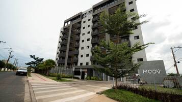 Un edificio residencial de varios pisos con un diseño moderno, con balcones y una entrada protegida por una reja.
