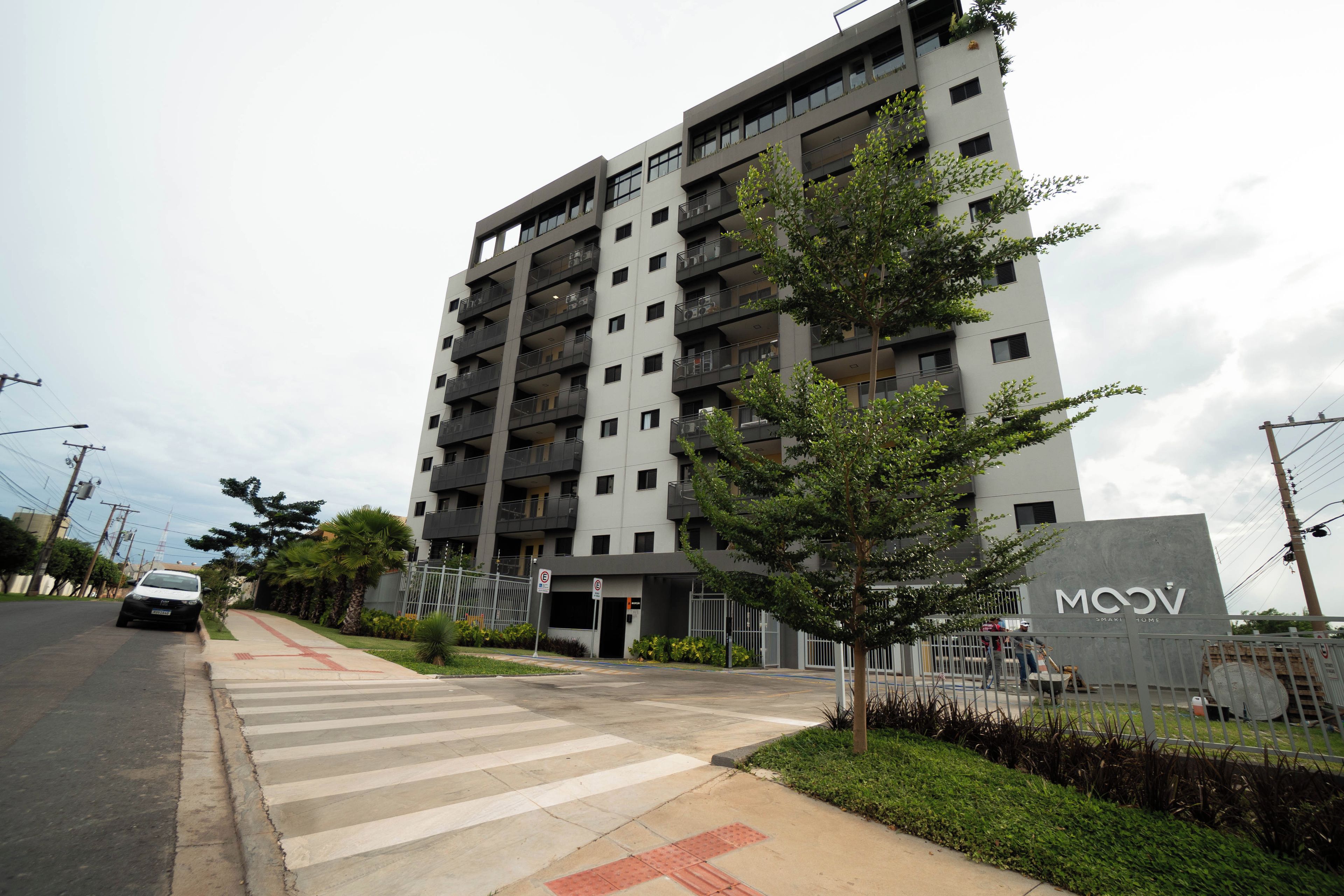 A multi-story residential building with a modern design, featuring balconies and a gated entrance.