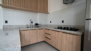 Una cocina moderna con armarios de madera, encimera de granito y estufa a gas empotrada.