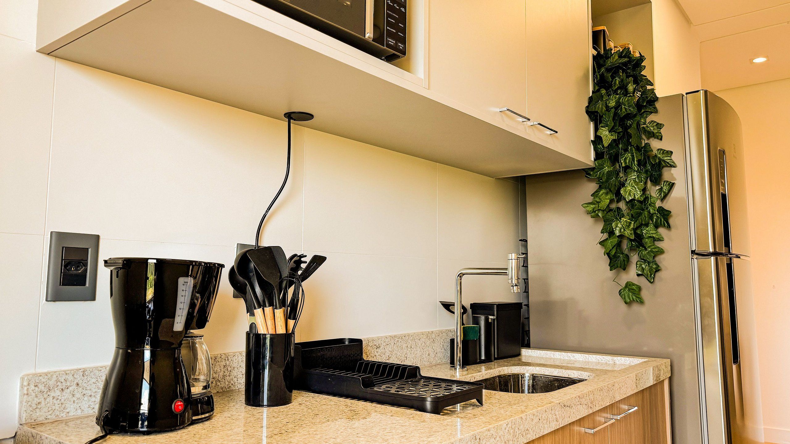 A modern kitchen with a built-in coffee maker, a kettle, and a kettle holder.