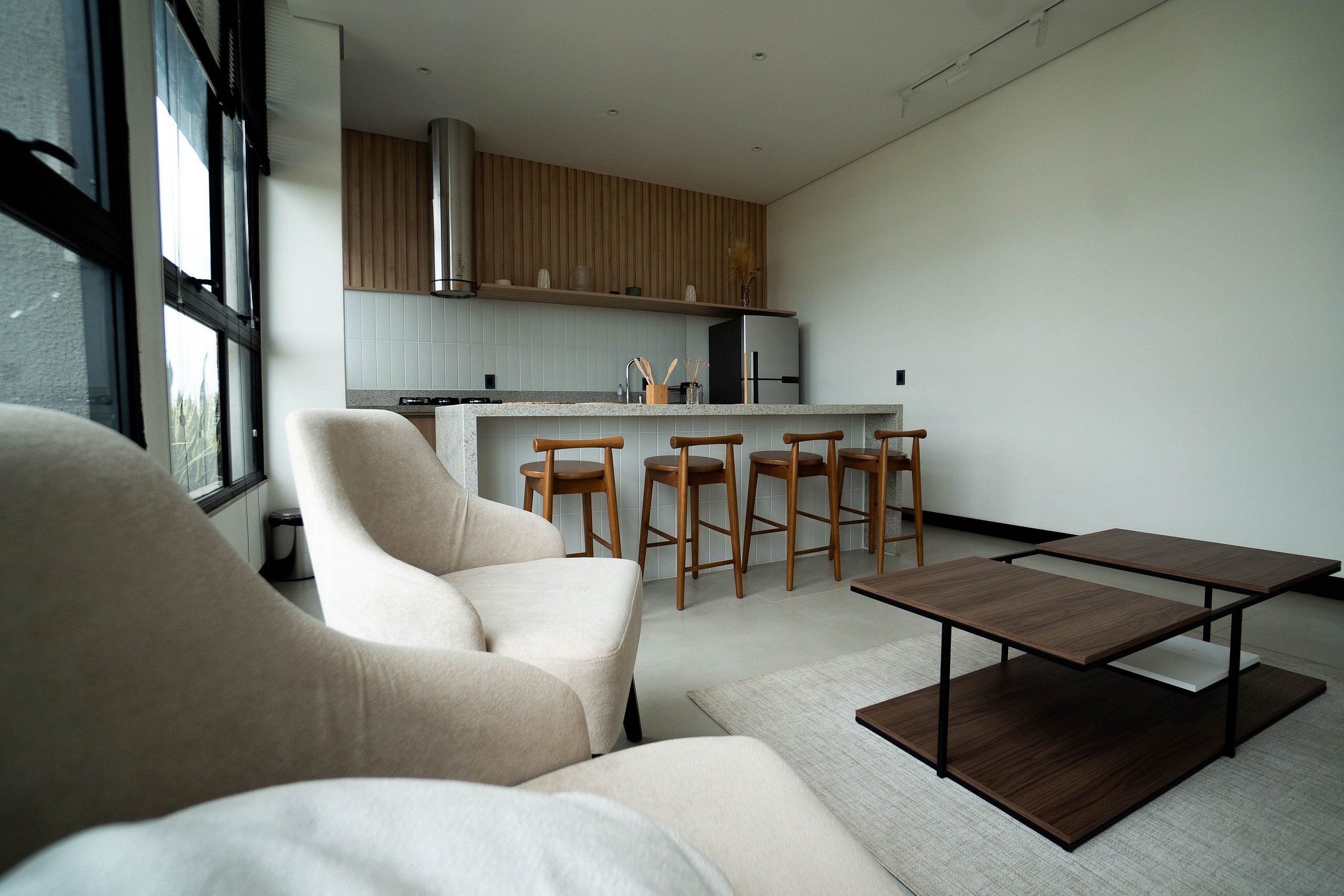 Una cocina moderna con una isla central, taburetes de madera y una mesa de comedor.
