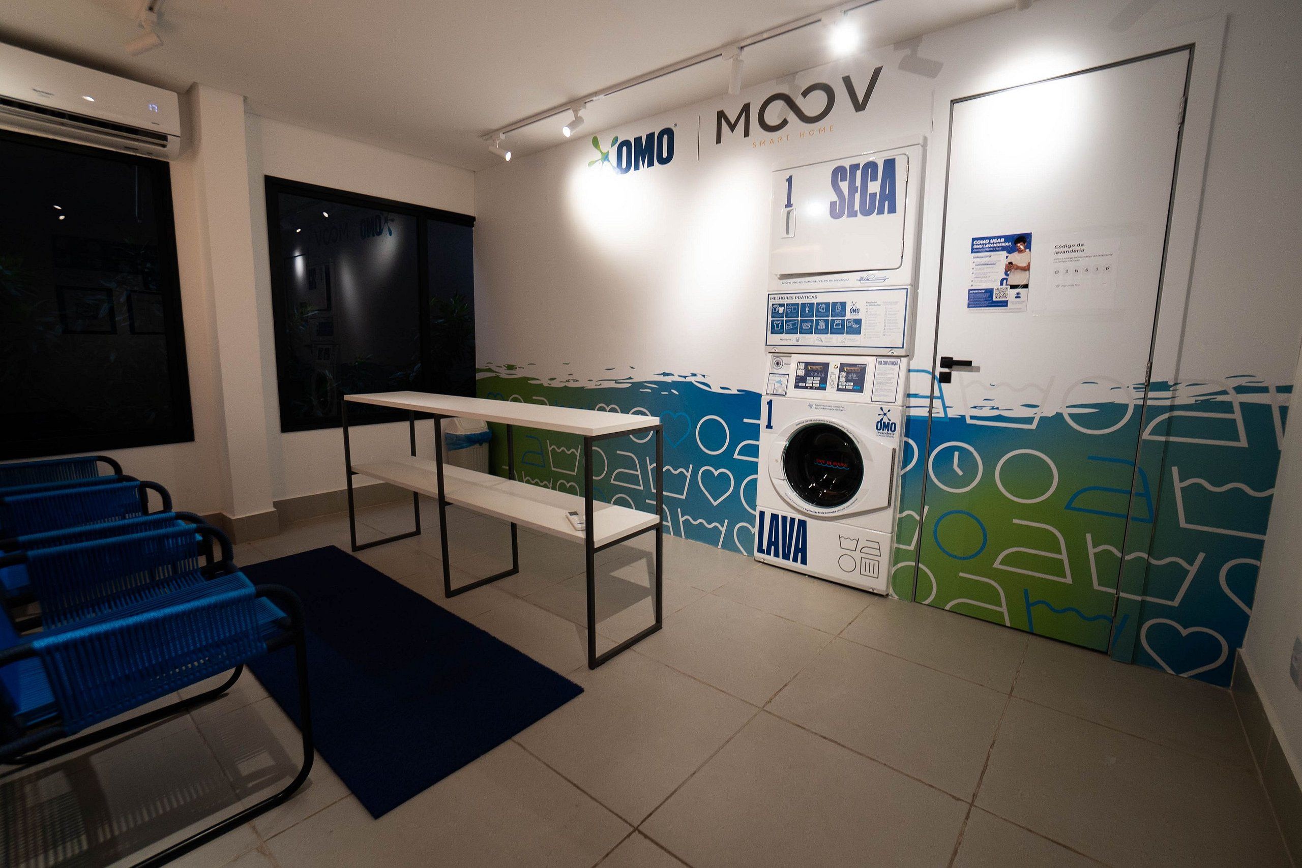 Un cuarto de lavado con una lavadora, un banco y una pared con diseño azul y verde.
