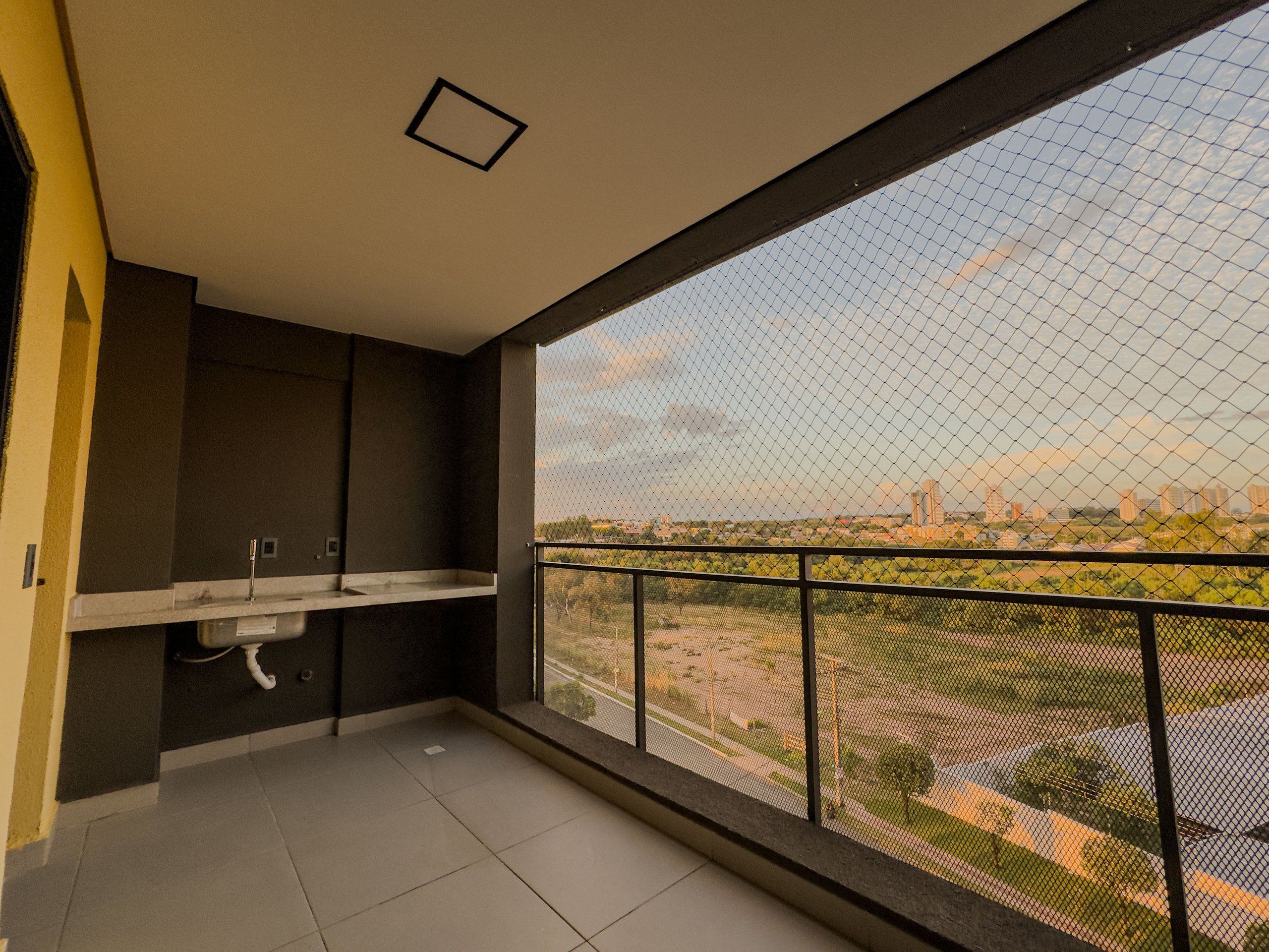 Un balcón con vista a un paisaje urbano y una pequeña zona con lavamanos.