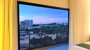 A room with a large window overlooking a cityscape at dusk.