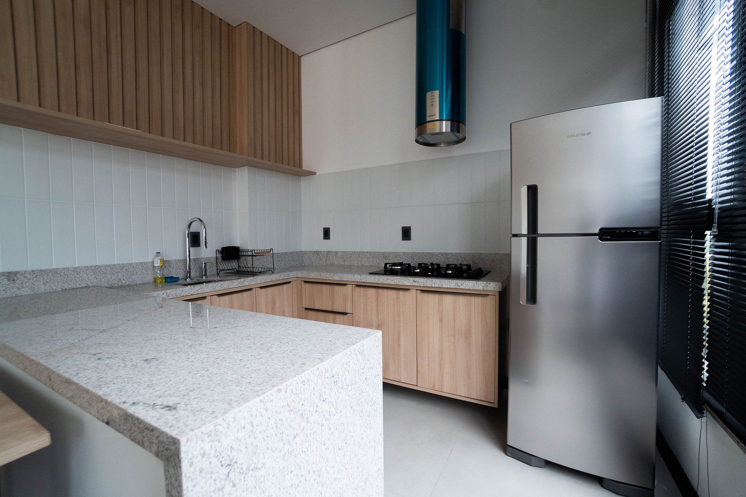 Una cocina moderna con un refrigerador de acero inoxidable, una estufa a gas y armarios de madera.