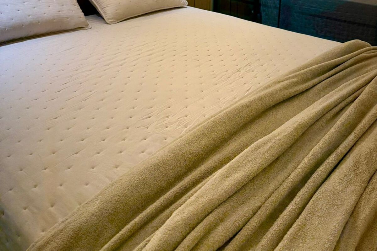 A hotel room with a bed, a nightstand, and a mirror.