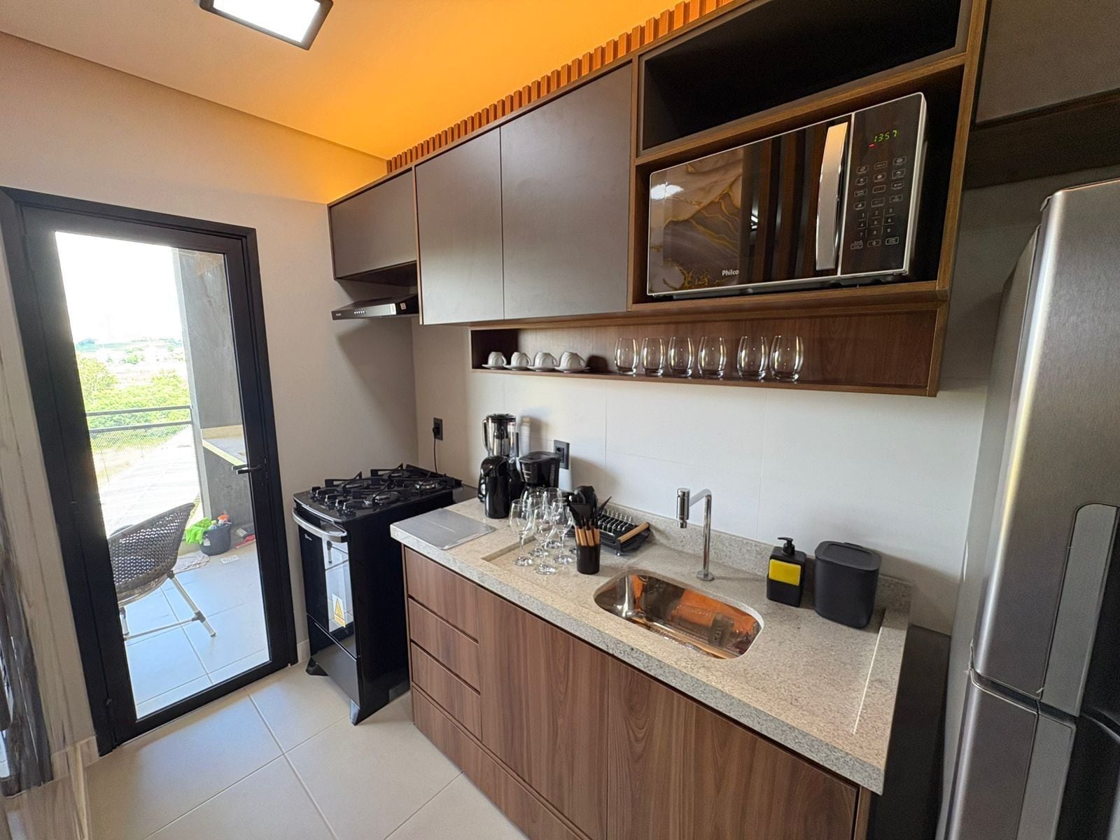 Una cocina moderna con estufa a gas, cafetera y microondas integrado.